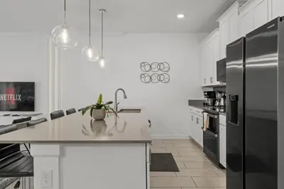 a kitchen with a stainless steel refrigerator and white cabinets at Casa moderna com piscina privativa perto da Disney in Kissimmee
