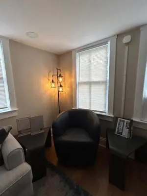 a living room with a black chair and two windows at Cute and Cozy Apt Near Historic Downtown Sanford in Sanford