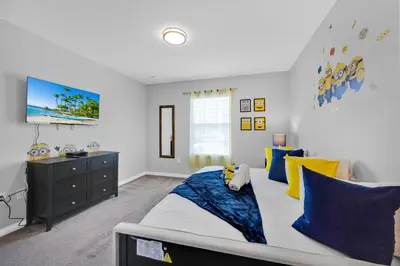 a bedroom with a bed with blue and yellow pillows at Disney Themed Home l Private Pool l Lazy River in Kissimmee