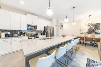 a kitchen with white cabinets and a large island with chairs at 4827#2 Casa com Quartos Temáticos e Piscina Privativa in Kissimmee