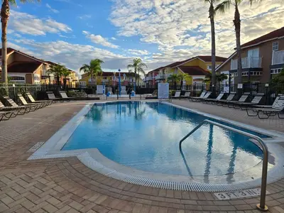a large swimming pool with chairs and palm trees at Kissimmee Vacation Beautiful Home in Kissimmee