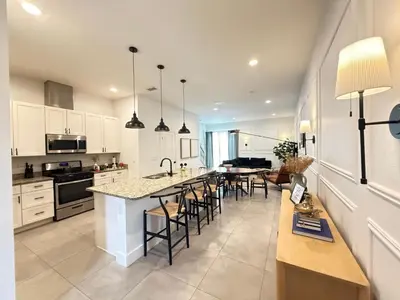a kitchen with white cabinets and a island with bar stools at Magical 4BR Escape - Pet-Friendly, 9 Min to Disney in Orlando