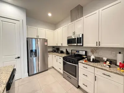 a kitchen with white cabinets and a stainless steel refrigerator at Magical 4BR Escape - Pet-Friendly, 9 Min to Disney in Orlando
