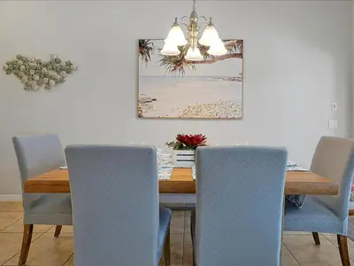a dining room table with chairs and a picture of a beach at Adorable Townhouse Completely Remodeled,3002Pp in Kissimmee