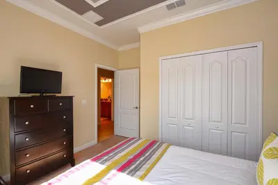 a bedroom with a bed and a dresser and a tv at Paradise Palms-5 Bed Townhome Wsplashpool-3045Pp in Kissimmee