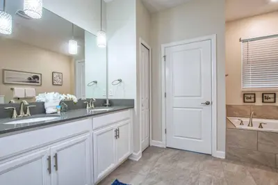 a bathroom with a sink and a mirror and a tub at Storey Lake 8 Bed Lake Front Pool Spa - 1684Str in Kissimmee