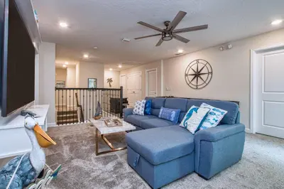a living room with a blue couch and a ceiling fan at Storey Lake 8 Bed Lake Front Pool Spa - 1684Str in Kissimmee