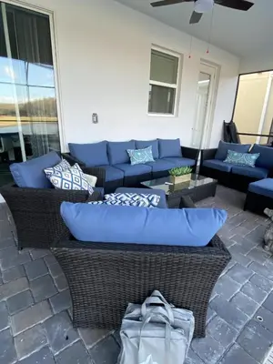 a couch sitting on a patio with blue pillows at Beautiful Brand New Waterfront Retreat!1689St in Kissimmee