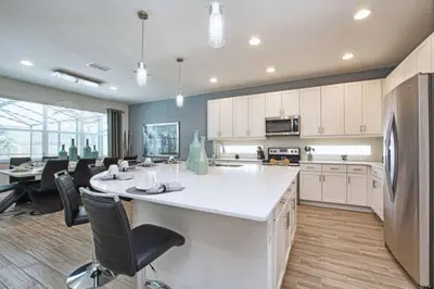 a kitchen with white cabinets and a large island with chairs at Sonoma - 6 Bedroom Pool Home- 1859Snr in Kissimmee