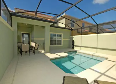 a house with a swimming pool and a table and chairs at Paradise Palms- 5 Bed Townhome Wsplashpool-3020Pp in Kissimmee
