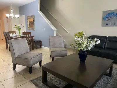 a living room with a couch and a table with flowers on it at Paradise Palms- 5 Bed Townhome Wsplashpool-3020Pp in Kissimmee
