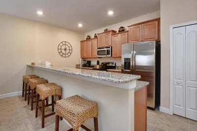 a kitchen with a counter with bar stools at Dog Friendly Townhouse With Splashpool 3610Pp in Kissimmee