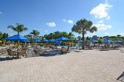 a patio with tables and chairs with blue umbrellas at Dog Friendly Townhouse With Splashpool 3610Pp in Kissimmee