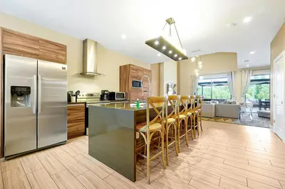 a kitchen with a stainless steel refrigerator and wooden cabinets at Magic Village Resort 5 Minutes to Disney!! in Orlando