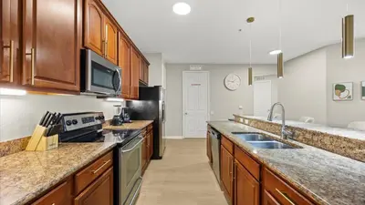 a large kitchen with wooden cabinets and stainless steel appliances at Upstay Spacious 3BR Home w Patio Vista Cay Resort in Orlando