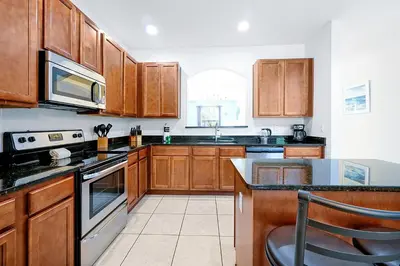 a kitchen with wooden cabinets and a stove top oven at Disney Dream at Veranda Palms Resort in Kissimmee