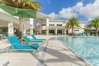 a pool with blue lounge chairs and a green umbrella at Disney Dream at Veranda Palms Resort in Kissimmee