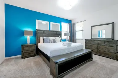 a bedroom with a large bed and a blue wall at Disney Dream at Veranda Palms Resort in Kissimmee