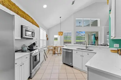 a large kitchen with white cabinets and a table at *Sun Palm Paradise* | Sleeps 14 | Near Disney! in Kissimmee