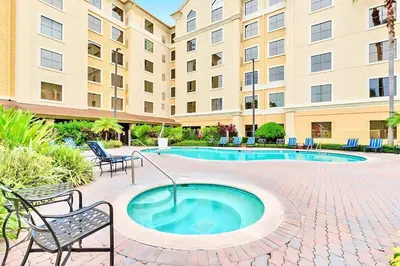 a swimming pool with chairs and a building at Chic Apartment near Disney w Pool Hot Tub Arcade in Orlando