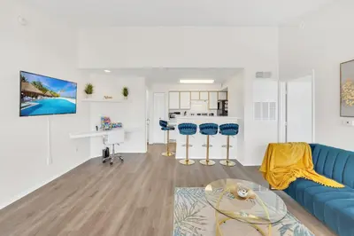 a living room with a blue couch and a kitchen at Elegant and cozy 2 BD condo near Disney in Kissimmee