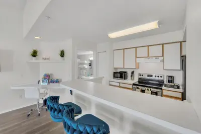 a kitchen with a white counter and blue chairs at Elegant and cozy 2 BD condo near Disney in Kissimmee