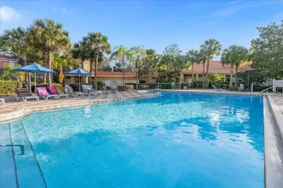 a large blue swimming pool with chairs and umbrellas at 3 Bedrooms 2 Bathrooms Encantada 3070 Wo in Kissimmee