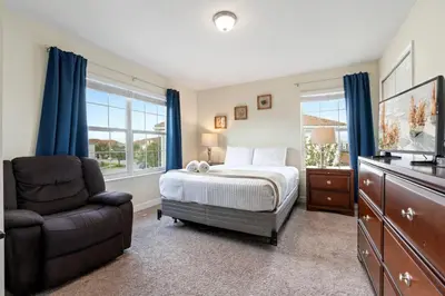 a bedroom with a bed and a chair and a television at Amazing 5Bdr House with pool 4857 in Kissimmee