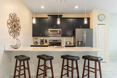 a kitchen with black cabinets and a counter with stools at Amazing 5Bdr House with pool 4857 in Kissimmee