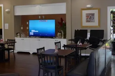 a dining room with tables and a large screen television at Luxury 4BDR House close to Parks in Kissimmee