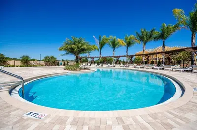 a swimming pool with chairs and palm trees at 3BR Disney Escape for Families in Kissimmee