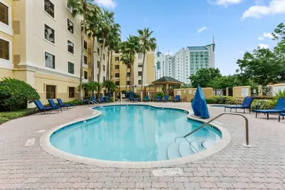 a swimming pool with blue chairs and a building at Hotel Room Next to Universal At Stay Sky Suites in Orlando