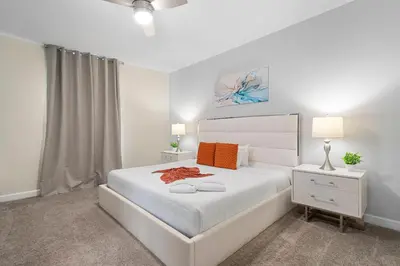a white bedroom with a white bed and two lamps at Family 5BR Retreat w Pool Near Disney in Kissimmee