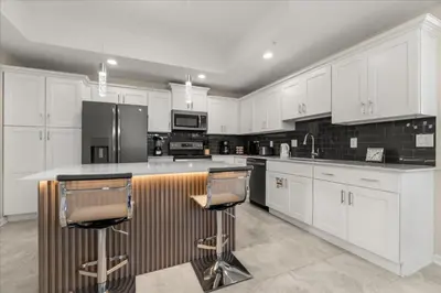 a kitchen with white cabinets and a island with bar stools at 3 Bedrooms 2 Bathrooms Storey Lake 3180-308 in Kissimmee