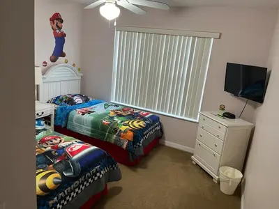 a small bedroom with two beds and a television at Home Away From Home in Kissimmee