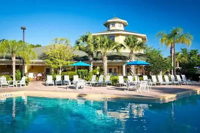 a resort with a pool and chairs and a building at 3BR Cozy Apartment at Caribe Cove Resort Near Disney! in Kissimmee