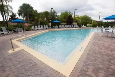 a large swimming pool with chairs and umbrellas at 3BR Cozy Apartment at Caribe Cove Resort Near Disney! in Kissimmee