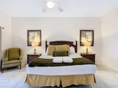 a bedroom with a large bed and two chairs at 3BR Cozy Apartment at Caribe Cove Resort Near Disney! in Kissimmee