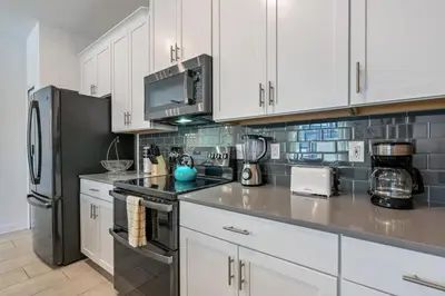 a kitchen with white cabinets and a black refrigerator at Casa c/ Piscina Privativa a 10min da Disney in Kissimmee
