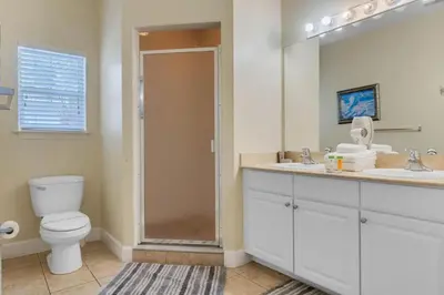 a bathroom with a toilet and a sink and a mirror at Cozy 4BR Disney vacation Home7-104 in Kissimmee