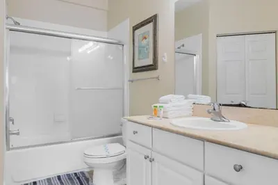 a white bathroom with a toilet and a sink at Cozy 4BR Disney vacation Home7-104 in Kissimmee