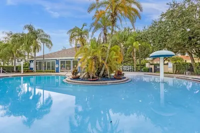 a large swimming pool with palm trees and a building at Cozy 4BR Disney vacation Home7-104 in Kissimmee