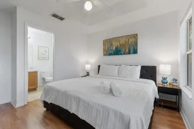 a white bedroom with a large bed with two white towels at Cozy 3BDR House near Disney - AL in Orlando