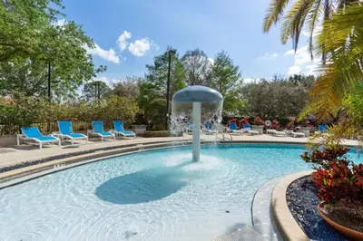 a pool with a fountain with blue lounge chairs at Your Home near Disney 19106 in Kissimmee