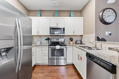 a kitchen with white cabinets and a stainless steel refrigerator at amazing 4bdr house near Disney in Kissimmee