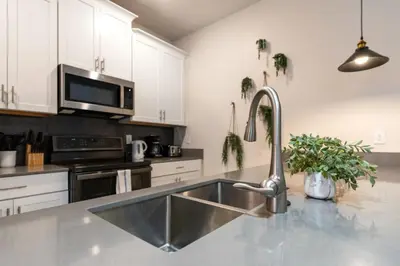a kitchen with a stainless steel sink and white cabinets at Outstanding 5BDR Disney Vacation in Kissimmee