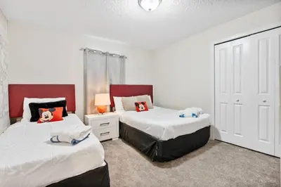 two beds in a bedroom with white and red at Outstanding 5BDR Disney Vacation in Kissimmee