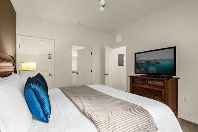 a bedroom with a bed with a blue pillow and a flat screen tv at Luxury 4 BDR House near Disney 11105 in Kissimmee