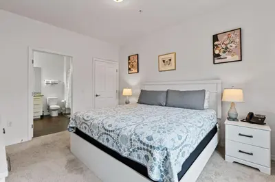 a white bedroom with a bed and a bathroom at Amazing 4BDR few miles from Disney in Kissimmee