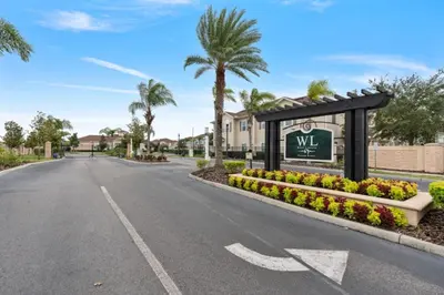 a street in a villa with a welcome sign and palm trees at Amazing 4BDR few miles from Disney in Kissimmee